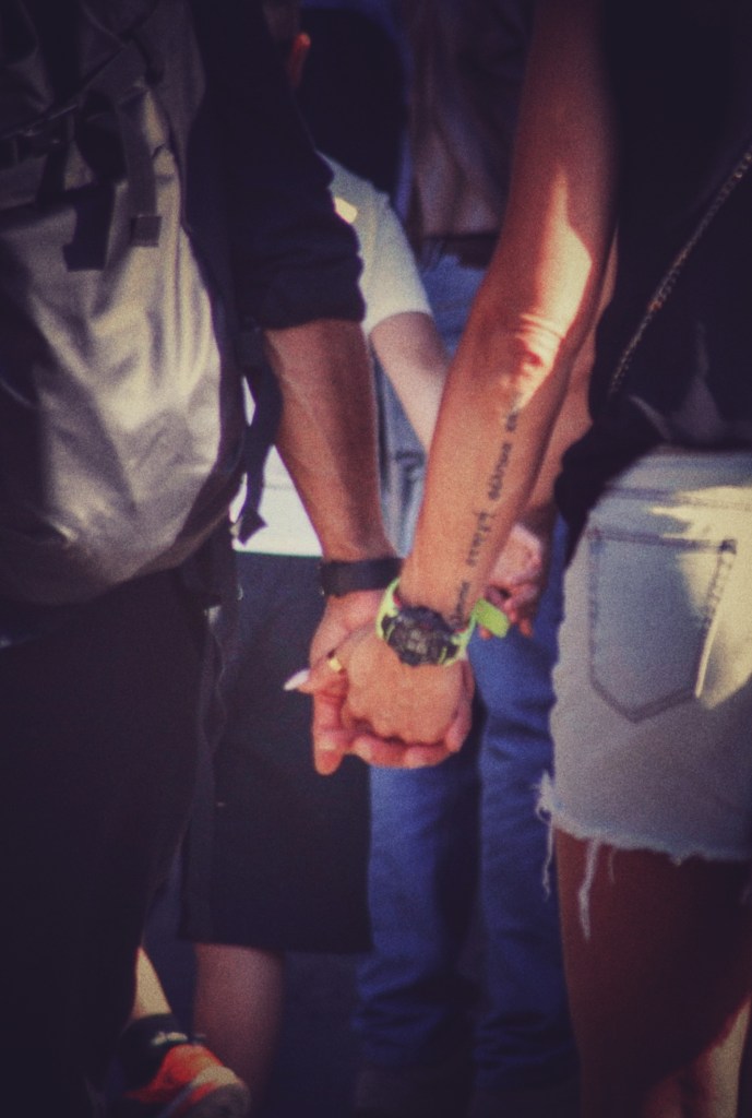 Due persone che si tengono per mano mentre camminano in una folla.