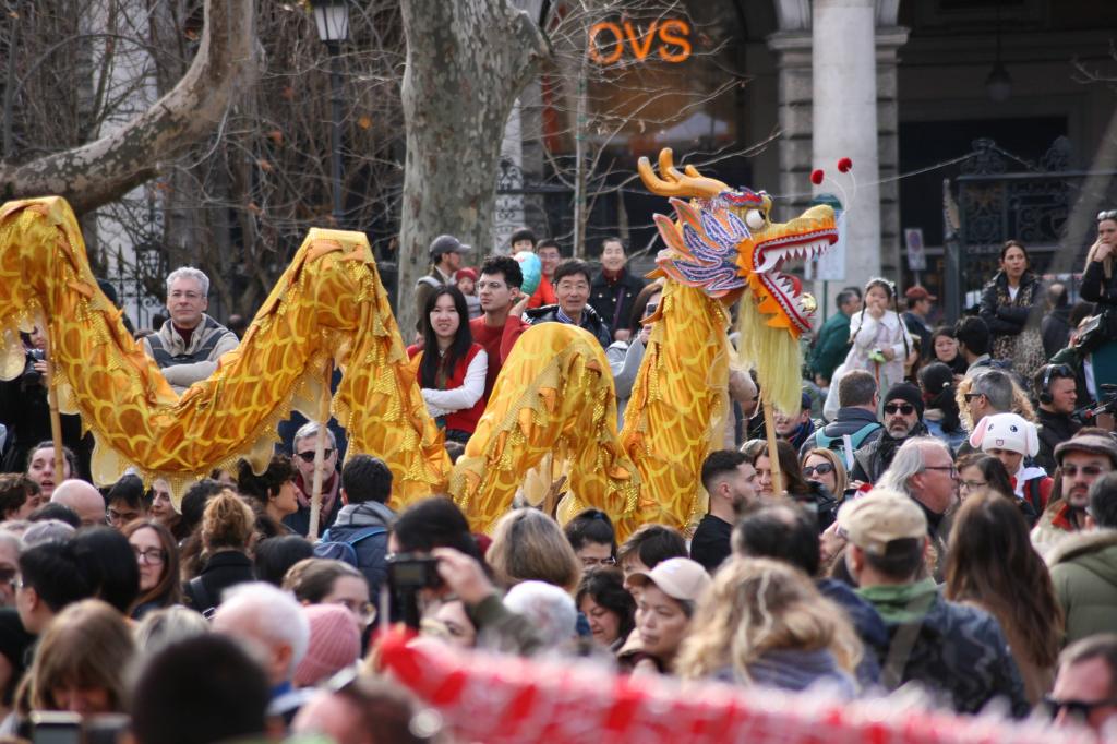 Una parata in cui viene presentato un drago cinese dorato, circondato da una grande folla di persone che osservano l'evento.